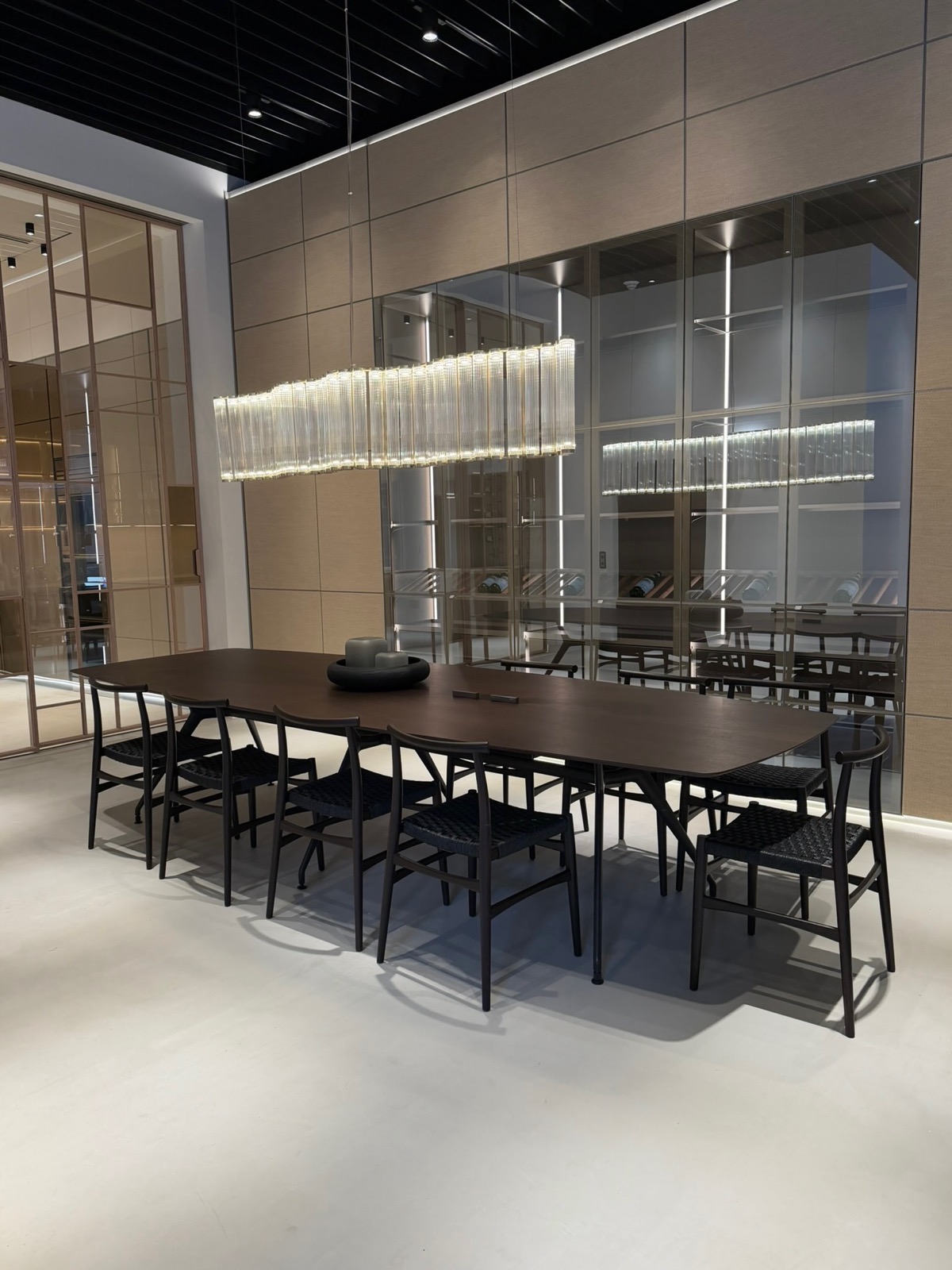 A formal dining table under a glass chandelier, framed by glass doors