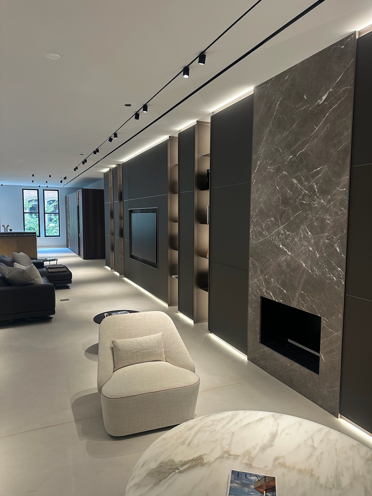 A living room along a stone fireplace wall and architectural shelving